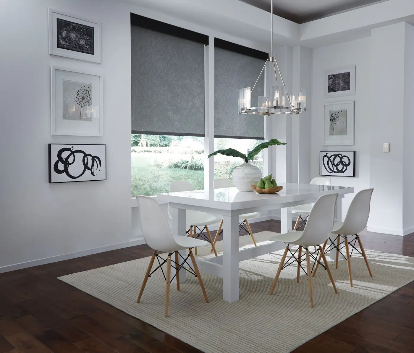 Modern dining room with motorized roller shades at mid-position softly filtering afternoon light, pendant chandelier, and Eames-style chairs around a white table