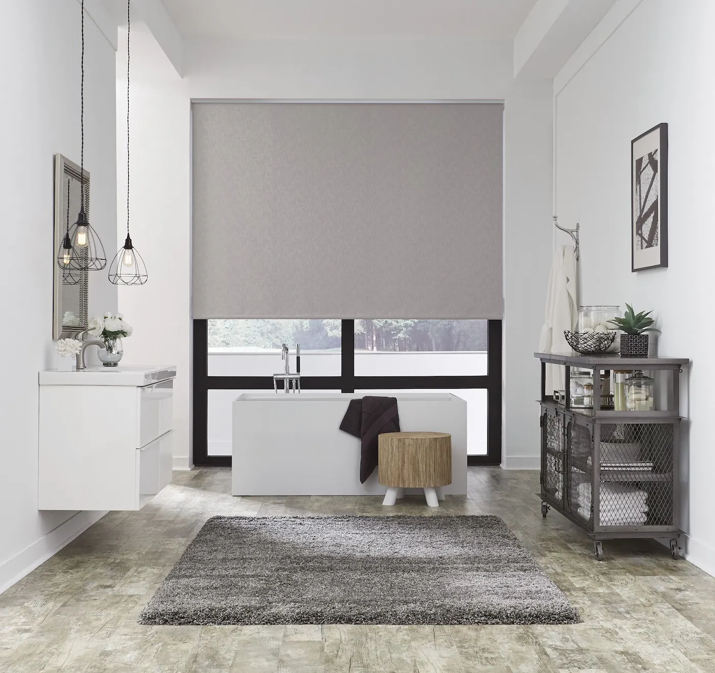 Elegant bathroom with a large grey motorized roller shade fully drawn above a freestanding soaking tub, pendant lights, and clean white walls